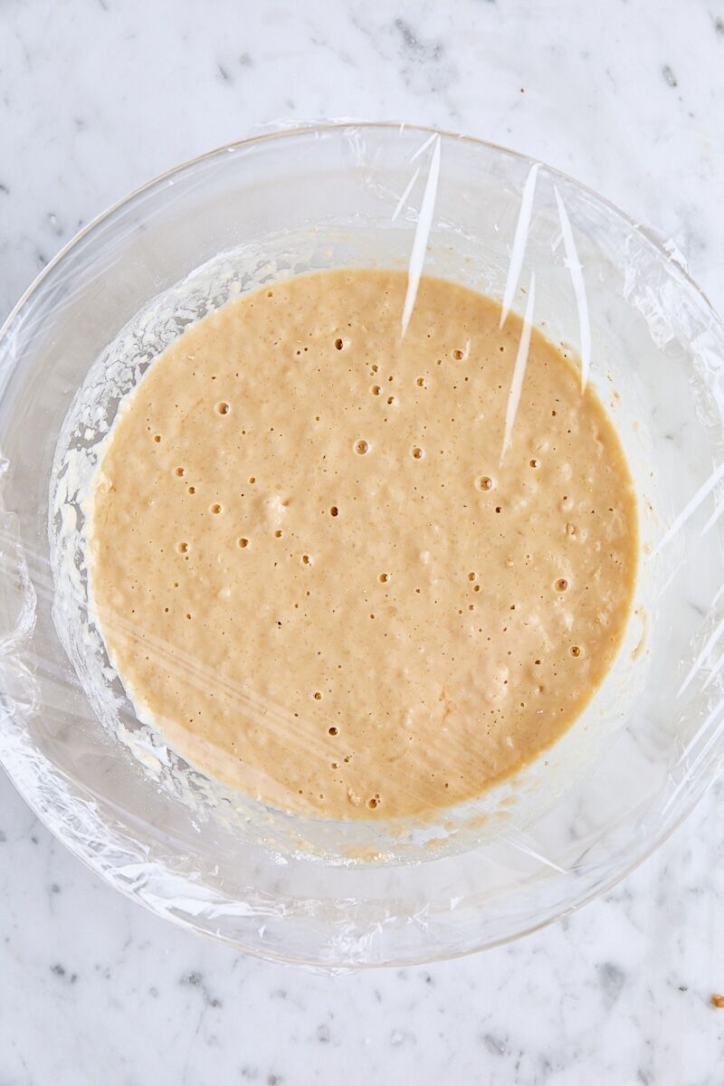 Waffle batter in large glass bowl with small bubbles on surface of batter