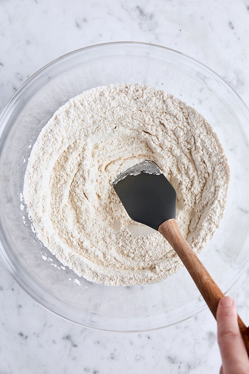 Dry ingredients in large glass bowl with spatula