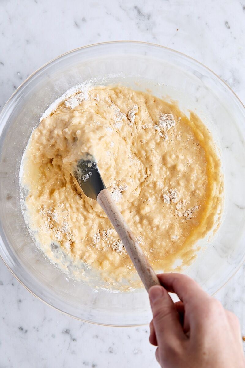 Folding wet and dry ingredients together in large glass bowl with spatula