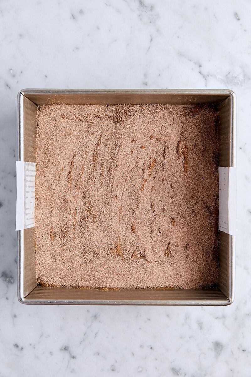 Blondie batter topped with cinnamon-sugar in parchment-lined square pan