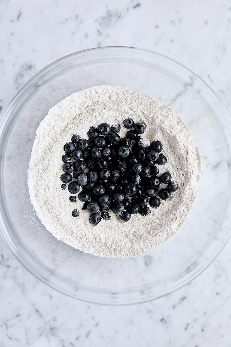 Blueberries added to dry ingredients in a large bowl