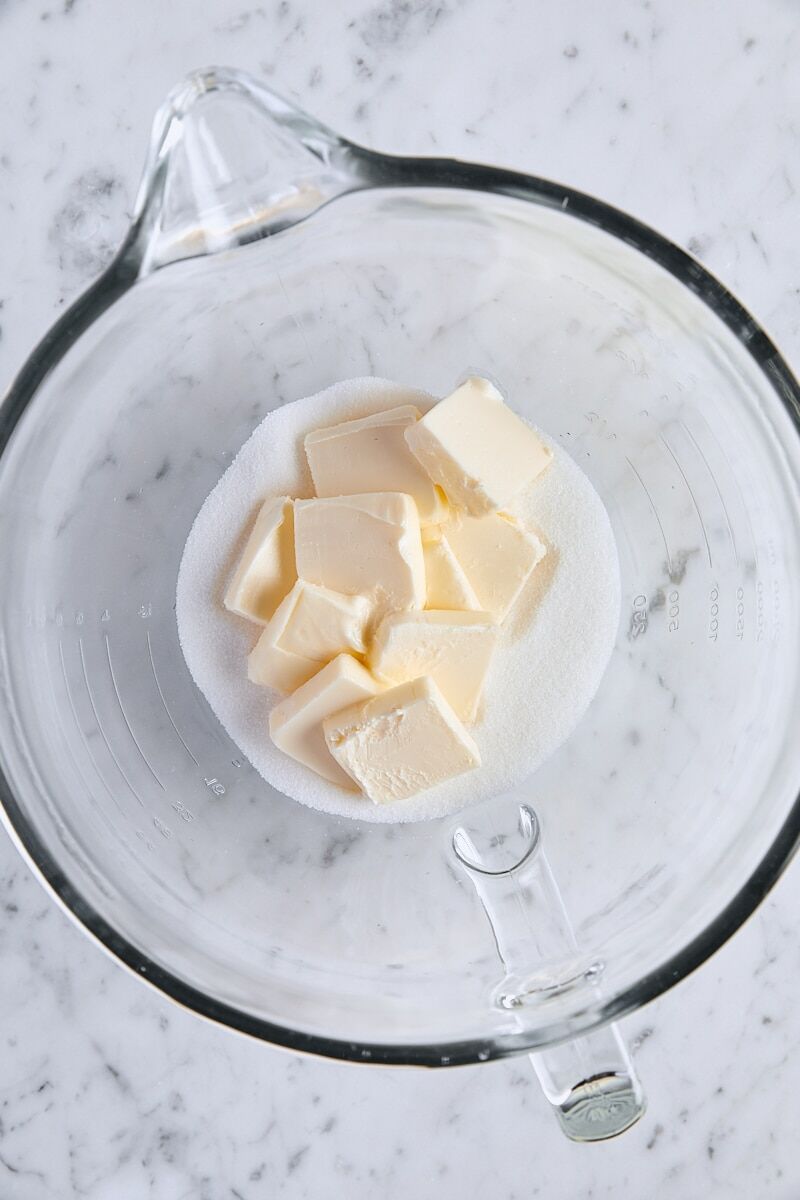 Room temperature butter and granulated sugar in glass mixing bowl