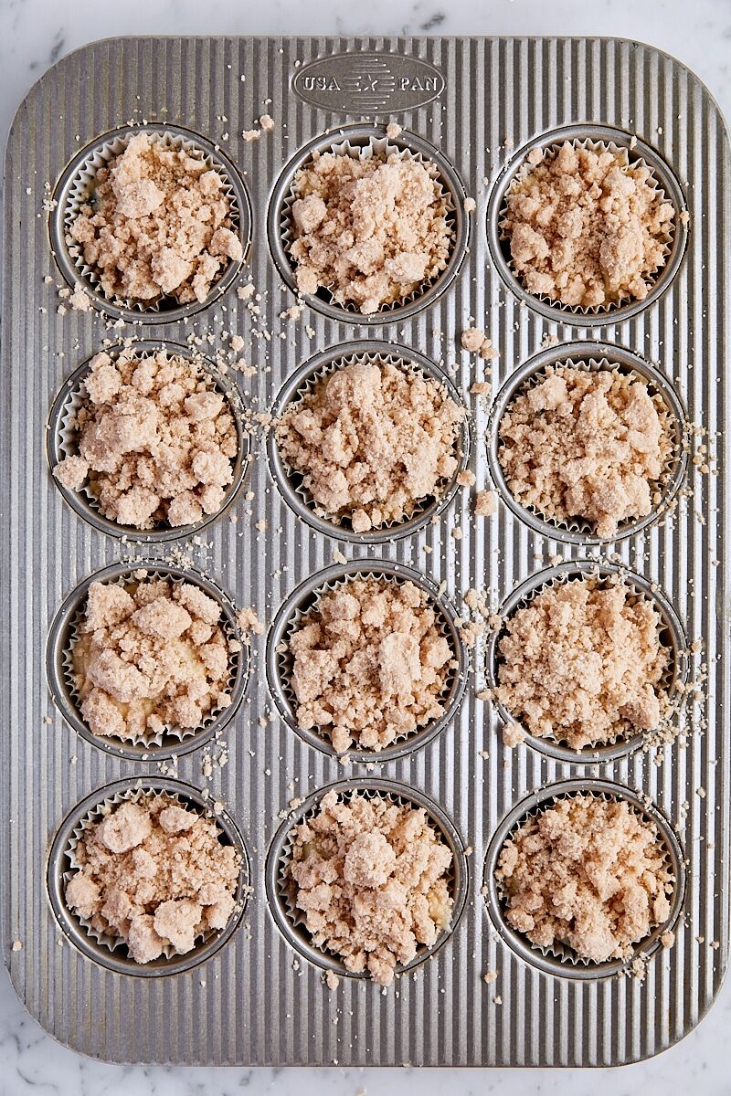 Blueberry muffin batter scooped into muffin tin and sprinkled with crumb topping