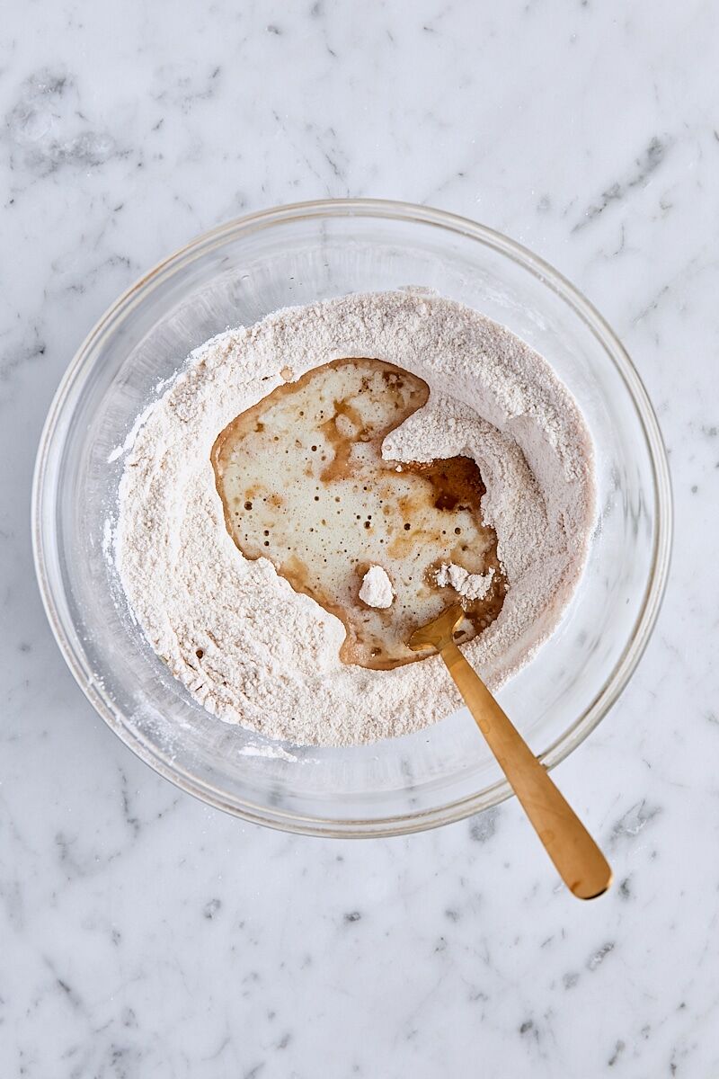 Melted butter and vanilla added to crumb topping ingredients in glass bowl
