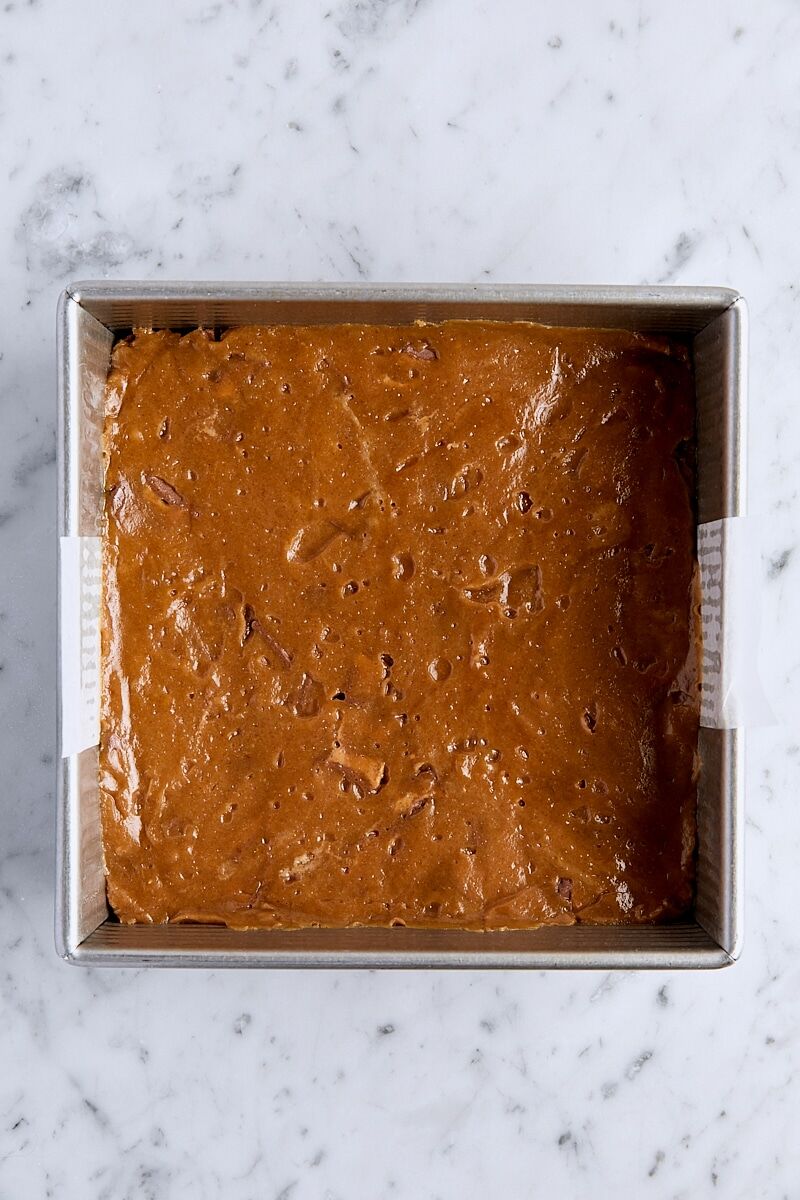 Peanut butter blondie batter in parchment-lined square pan