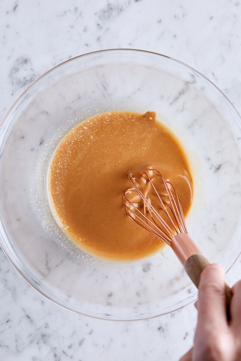 Melted butter and creamy peanut butter whisked together in glass bowl