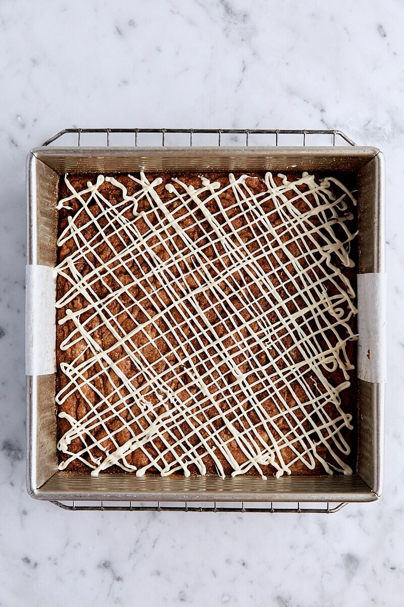 Blondies drizzle with white chocolate in parchment-lined square pan