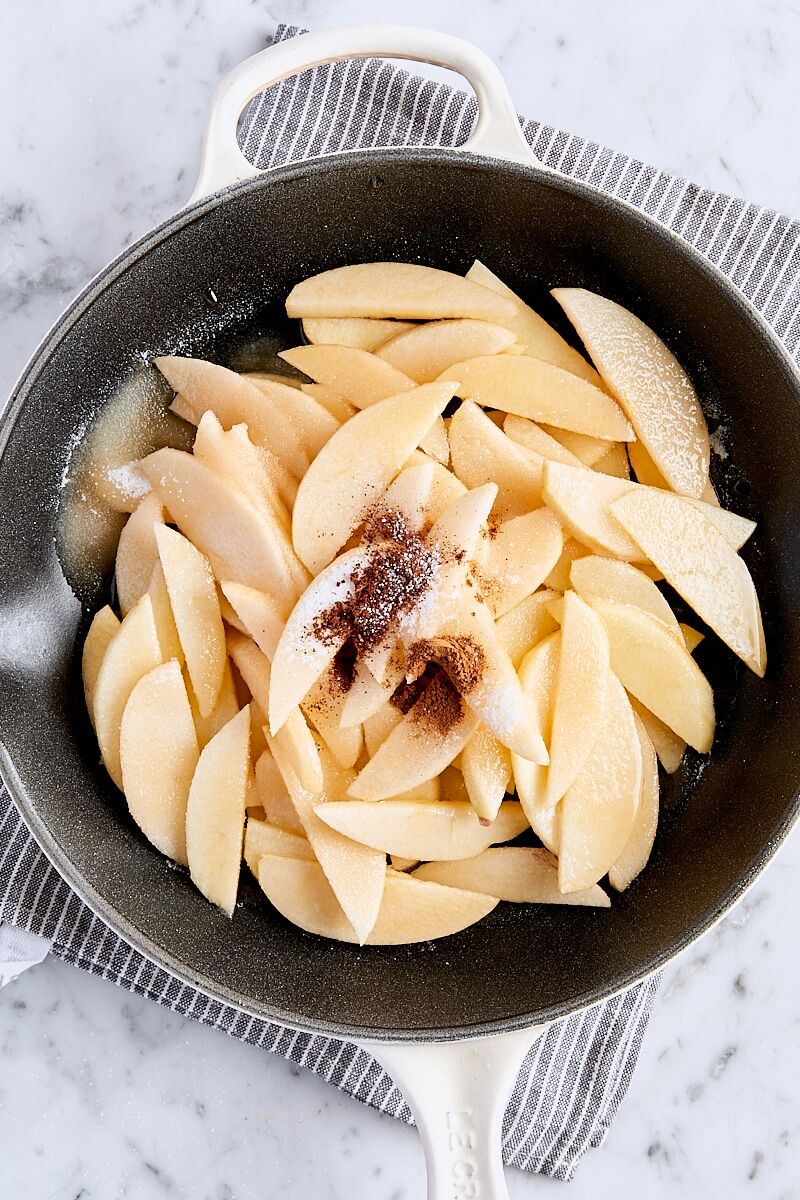 Sliced apples, sugar, spices, melted butter, maple syrup, cornstarch, and salt in skillet