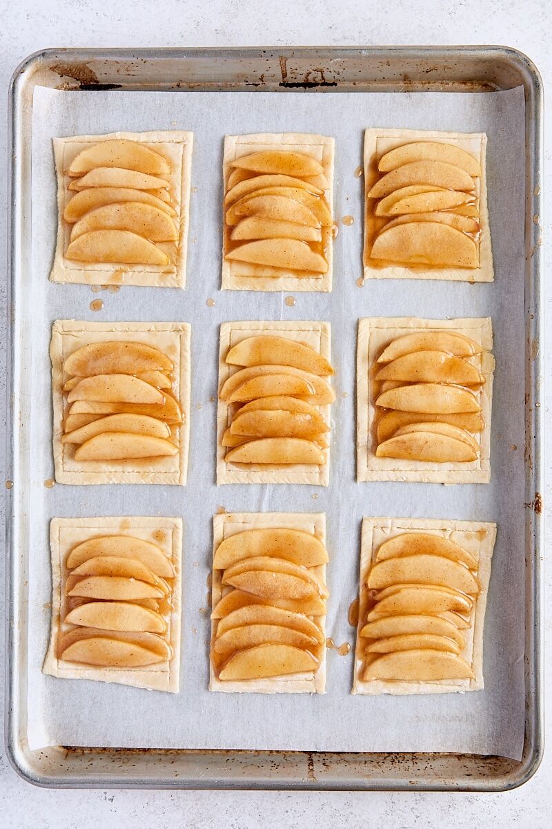 Assembled puff pastry apple tarts on parchment-lined baking sheet