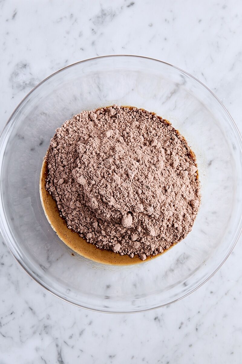 Brownie mix added to wet ingredients in glass bowl