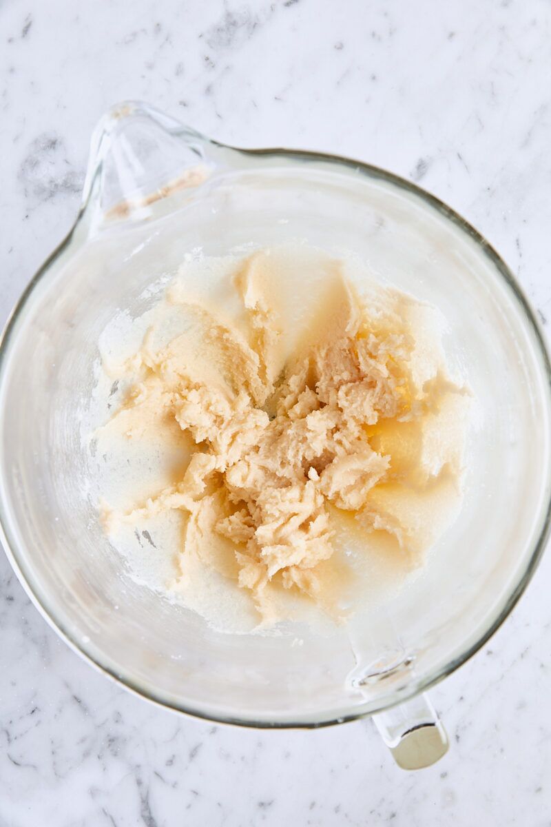 Butter, granulated sugar, and vanilla mixed together in glass mixing bowl
