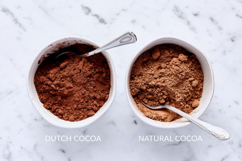 Dutch process cocoa in a small bowl with a spoon and natural cocoa in a small bowl with a spoon