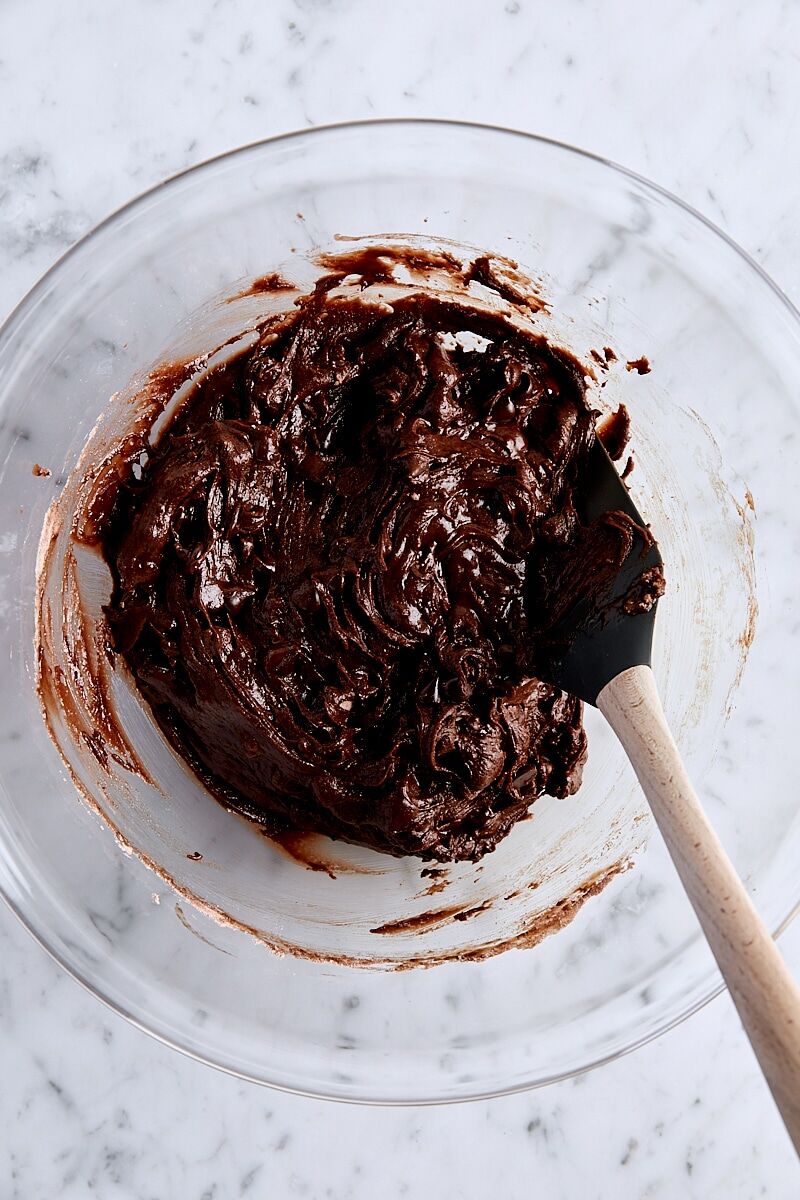 Mixed brownie batter in glass bowl with spatula