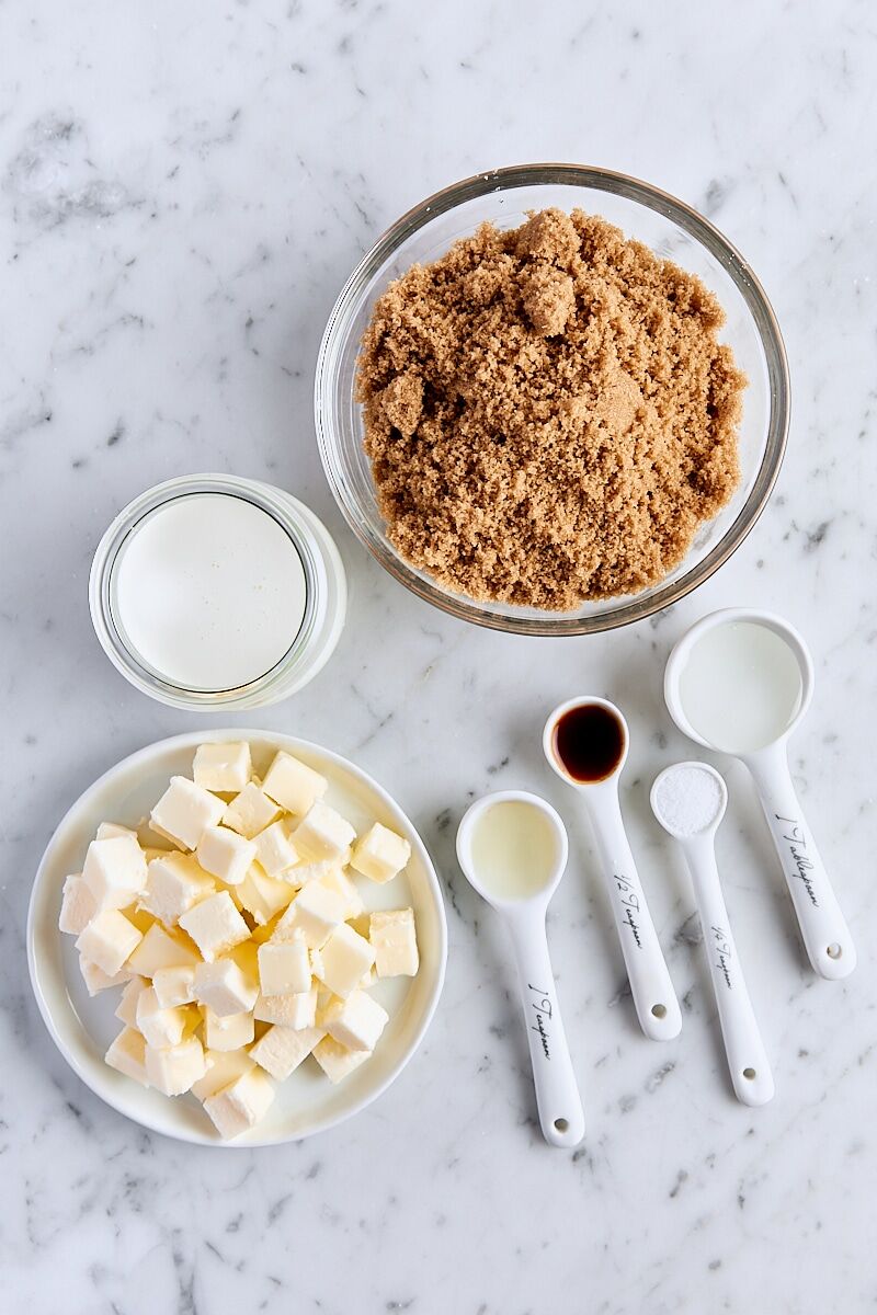 Ingredients for homemade butterscotch sauce on white marble background