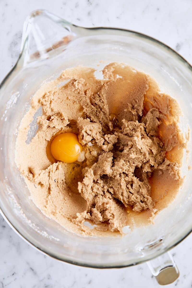 Egg added to cookie dough in glass mixing bowl