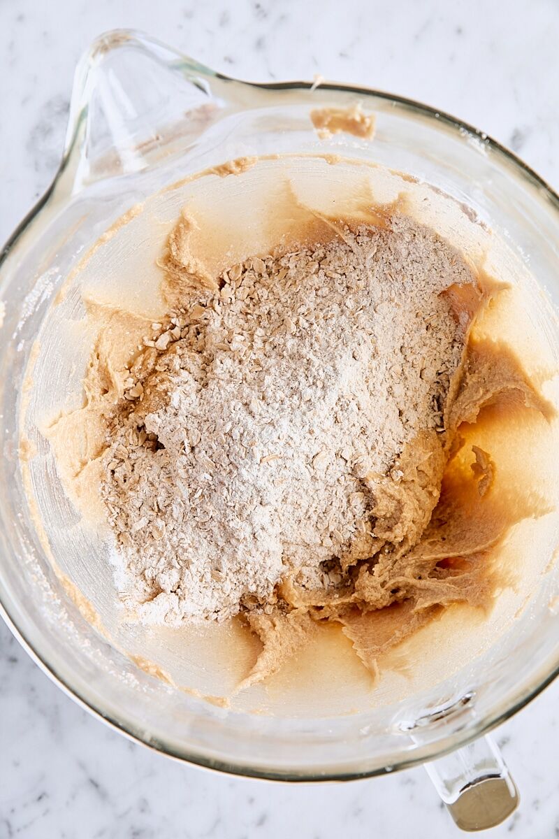 Dry ingredients added to cookie dough in glass mixing bowl