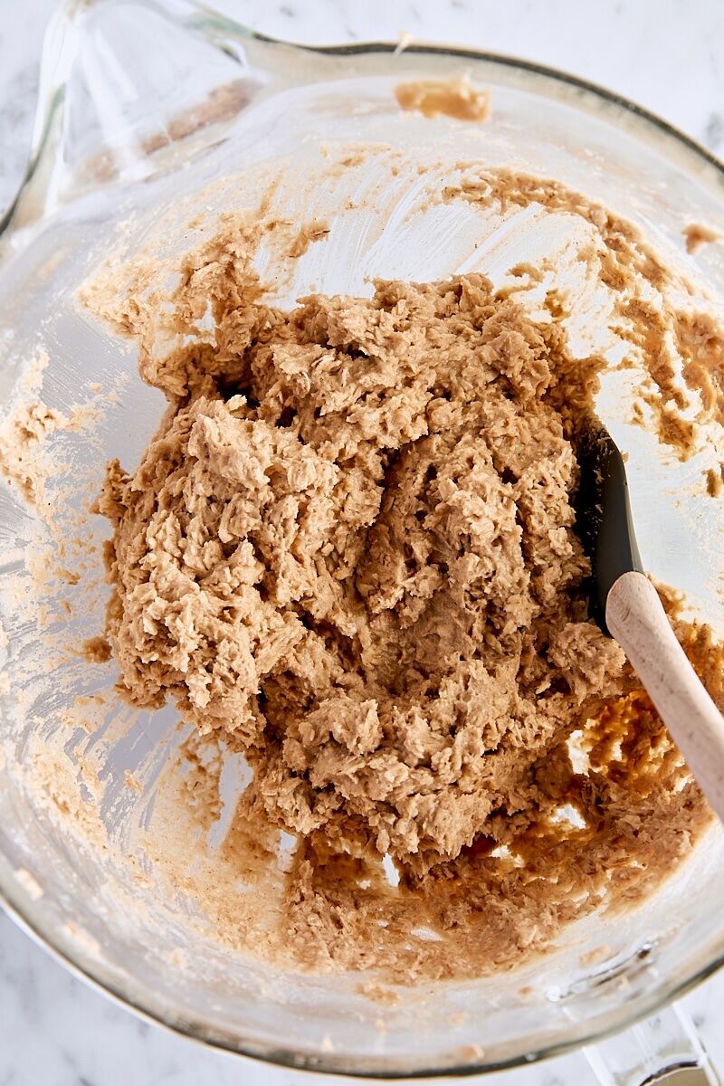 Oatmeal cookie dough in glass mixing bowl with spatula