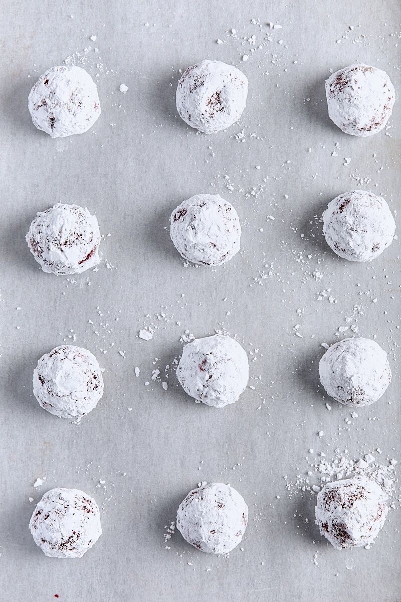 Red velvet cookie dough balls scooped onto parchment-lined baking sheet