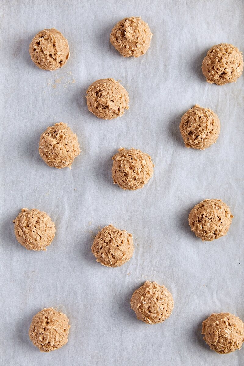 Oatmeal cookie dough balls scooped onto parchment-lined baking sheet