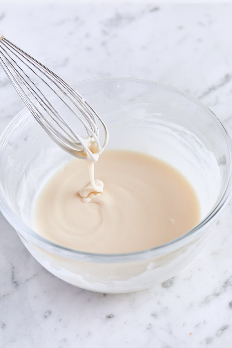 Vanilla icing whisked together in glass bowl