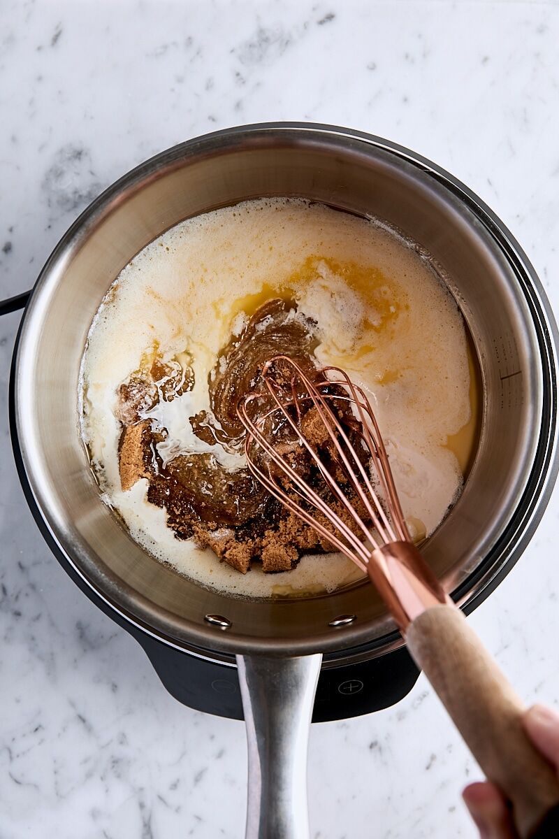 Whisking together melted butter, dark brown sugar, heavy cream, and lemon in saucepan