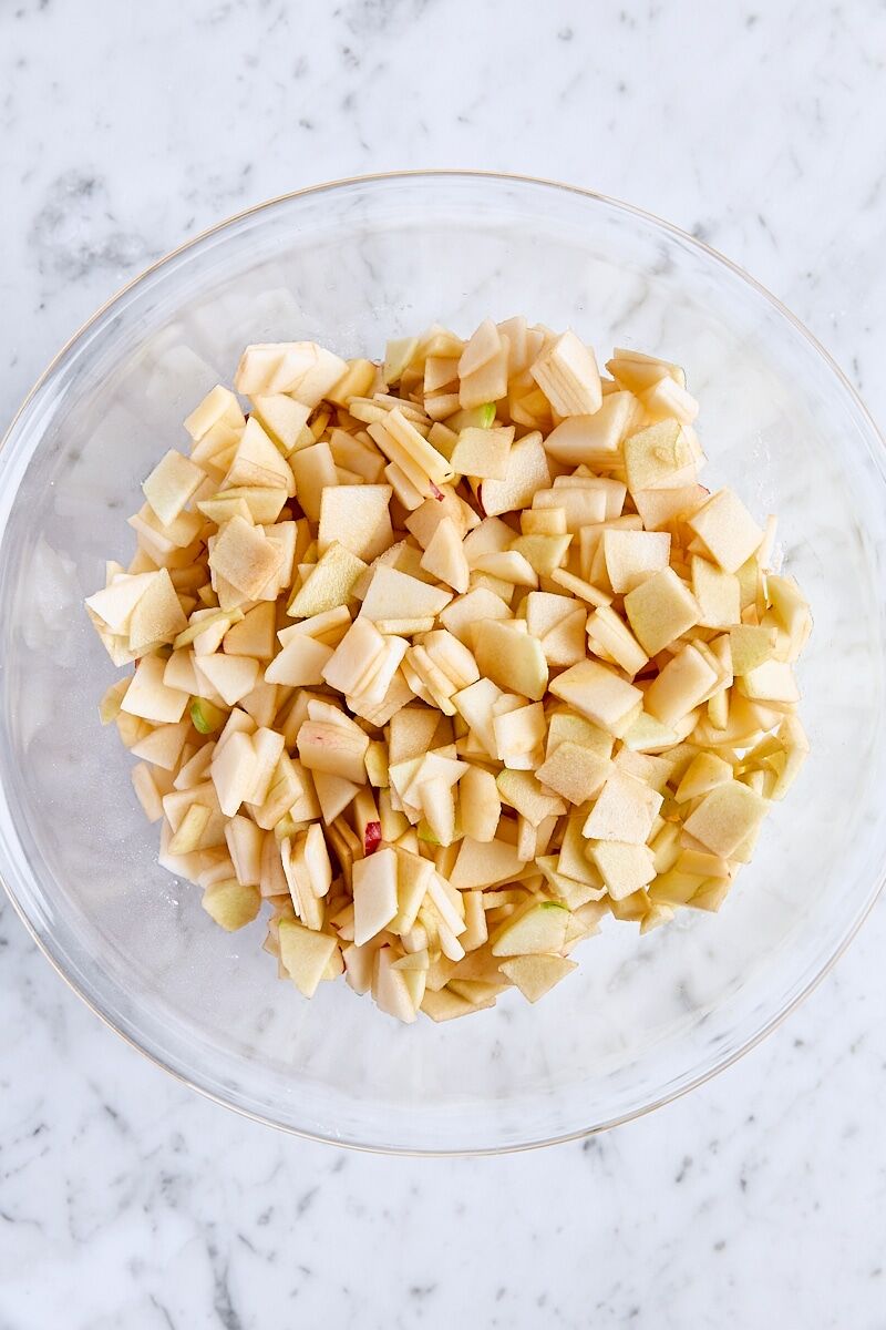 Apples added to sugar mixture in large glass bowl