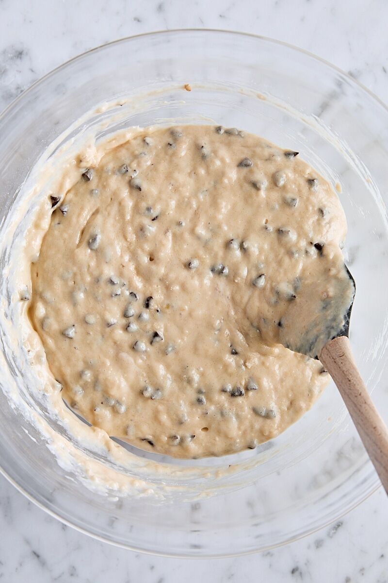 Mixed banana bread muffin batter in large glass bowl with spatula