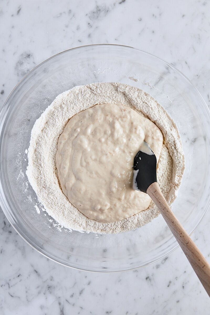 Banana mixture added to flour mixture in large glass bowl