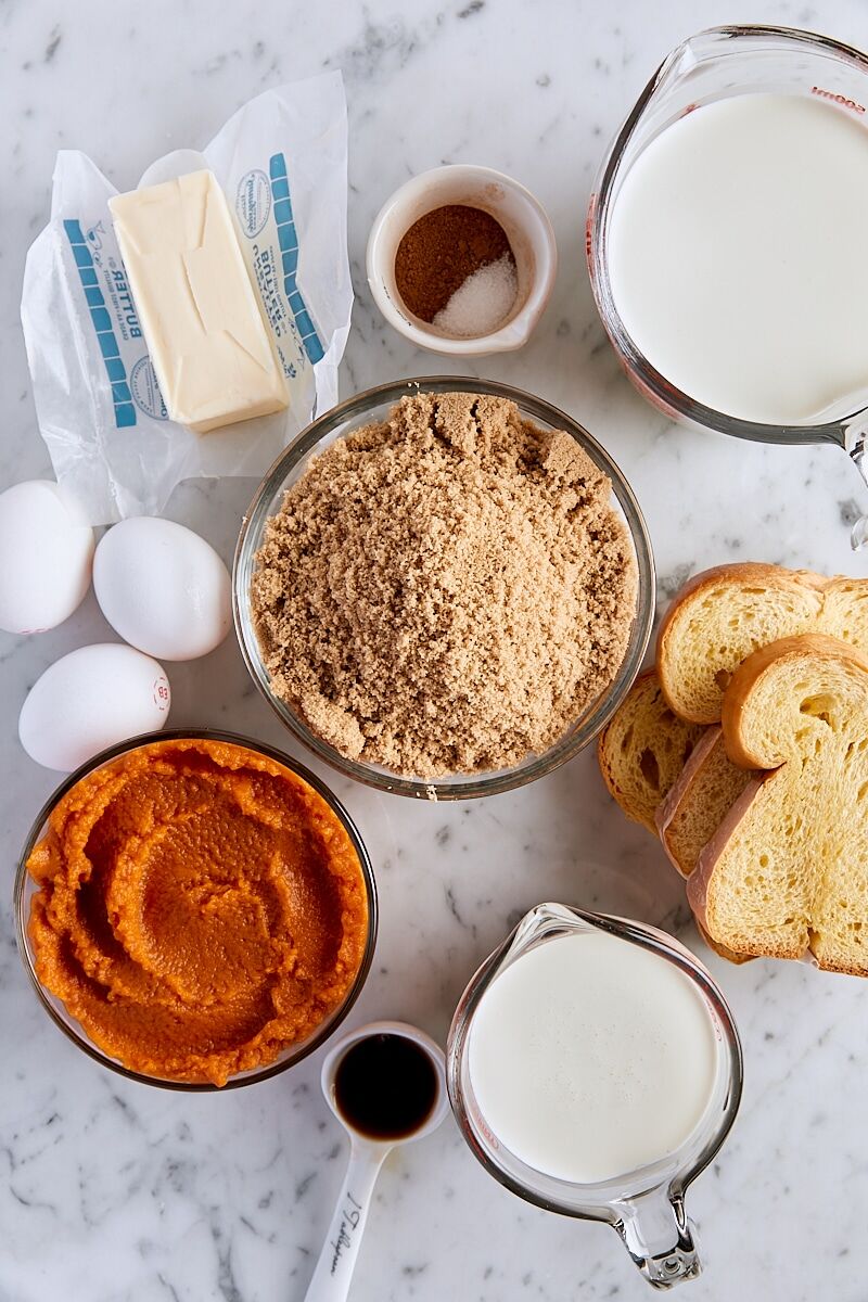 Ingredients for pumpkin bread pudding on white marble background