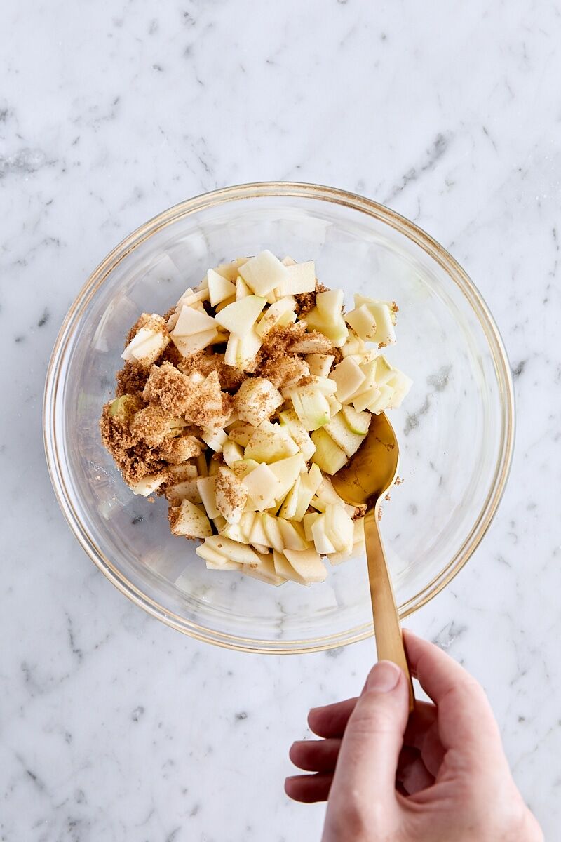 Tossing chopped apples with dark brown sugar in a small bowl