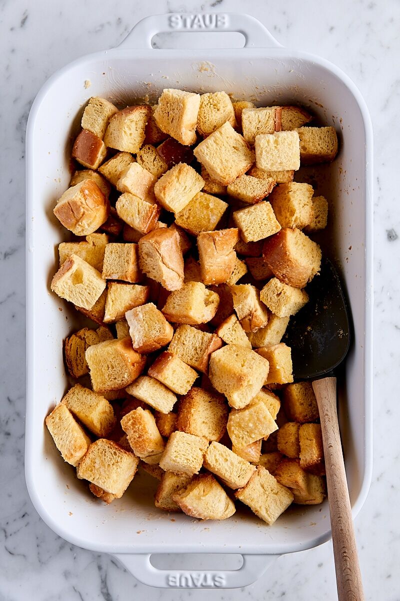Brioche cubes coated with melted butter in baking dish