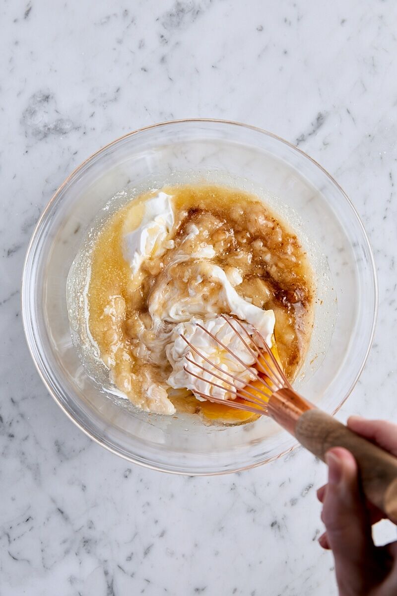 Mashed ripe banana, sour cream, unsalted butter, egg, and vanilla extract in glass bowl