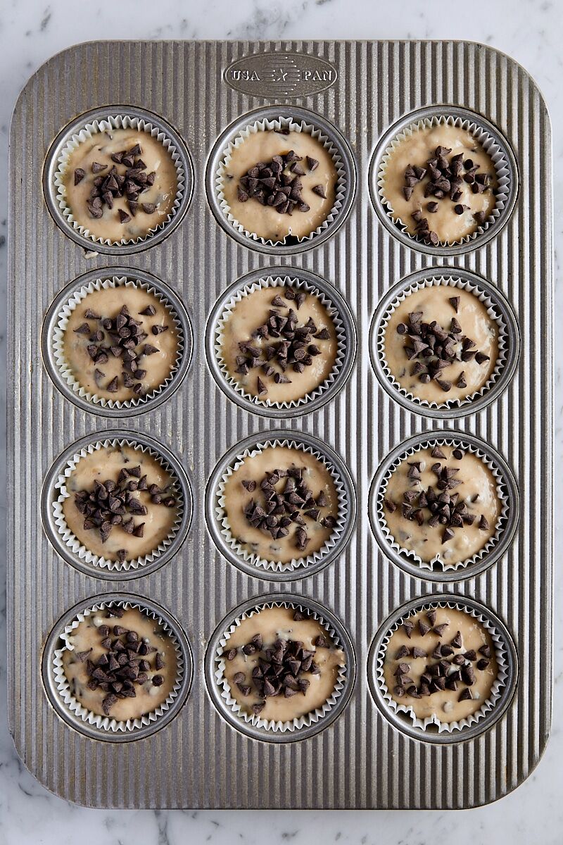 Banana bread muffin batter scooped into muffin tin and topped with chocolate chips