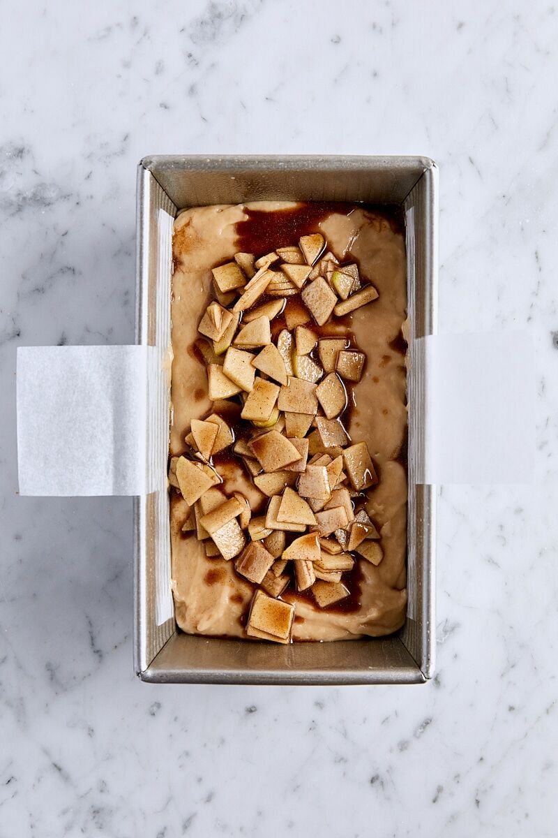 Assembled apple fritter bread in parchment-lined loaf pan