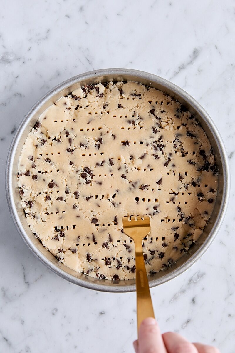 Chocolate chip shortbread dough pressed into round cake pan and pricked with fork