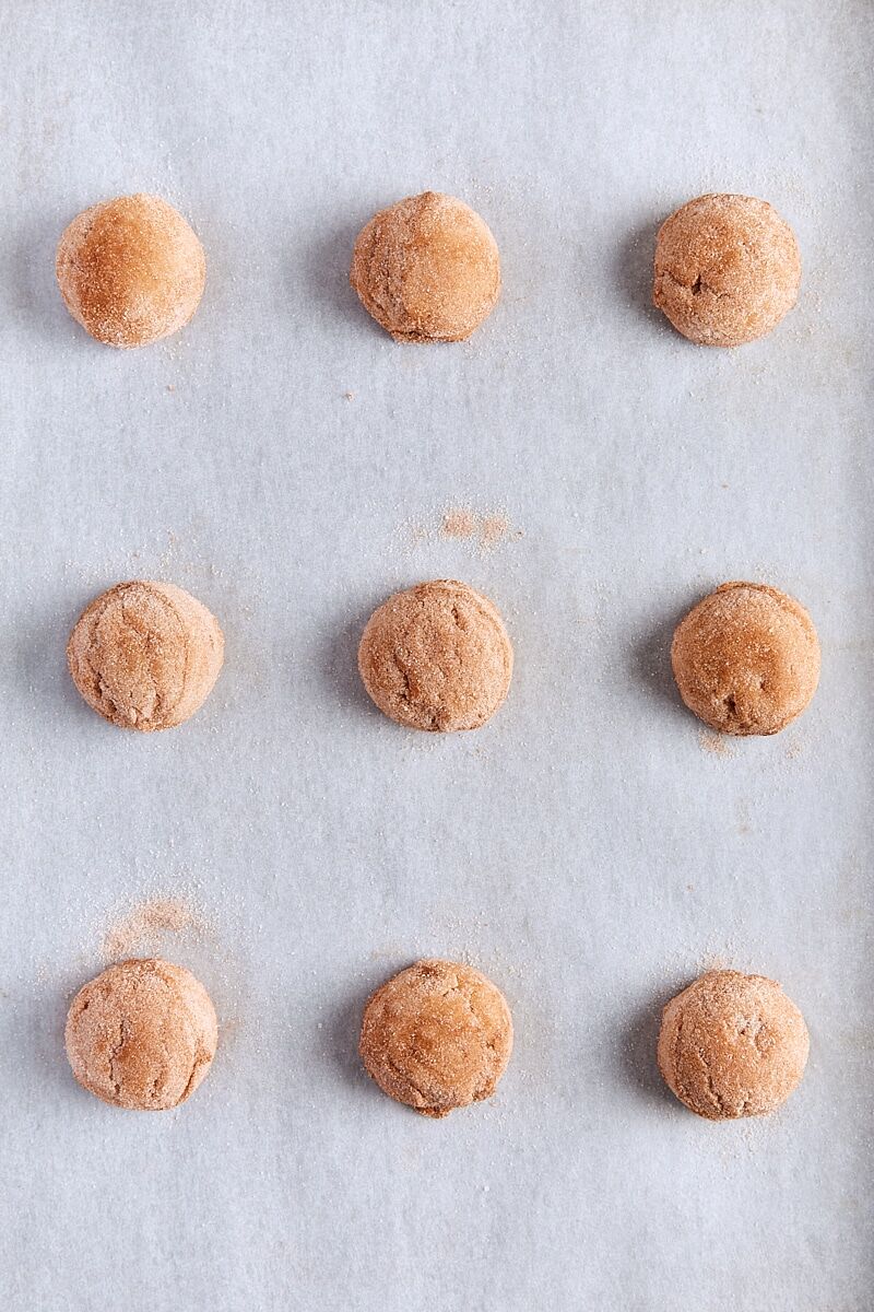 Snickerdoodle dough balls scooped onto parchment-lined baking sheet