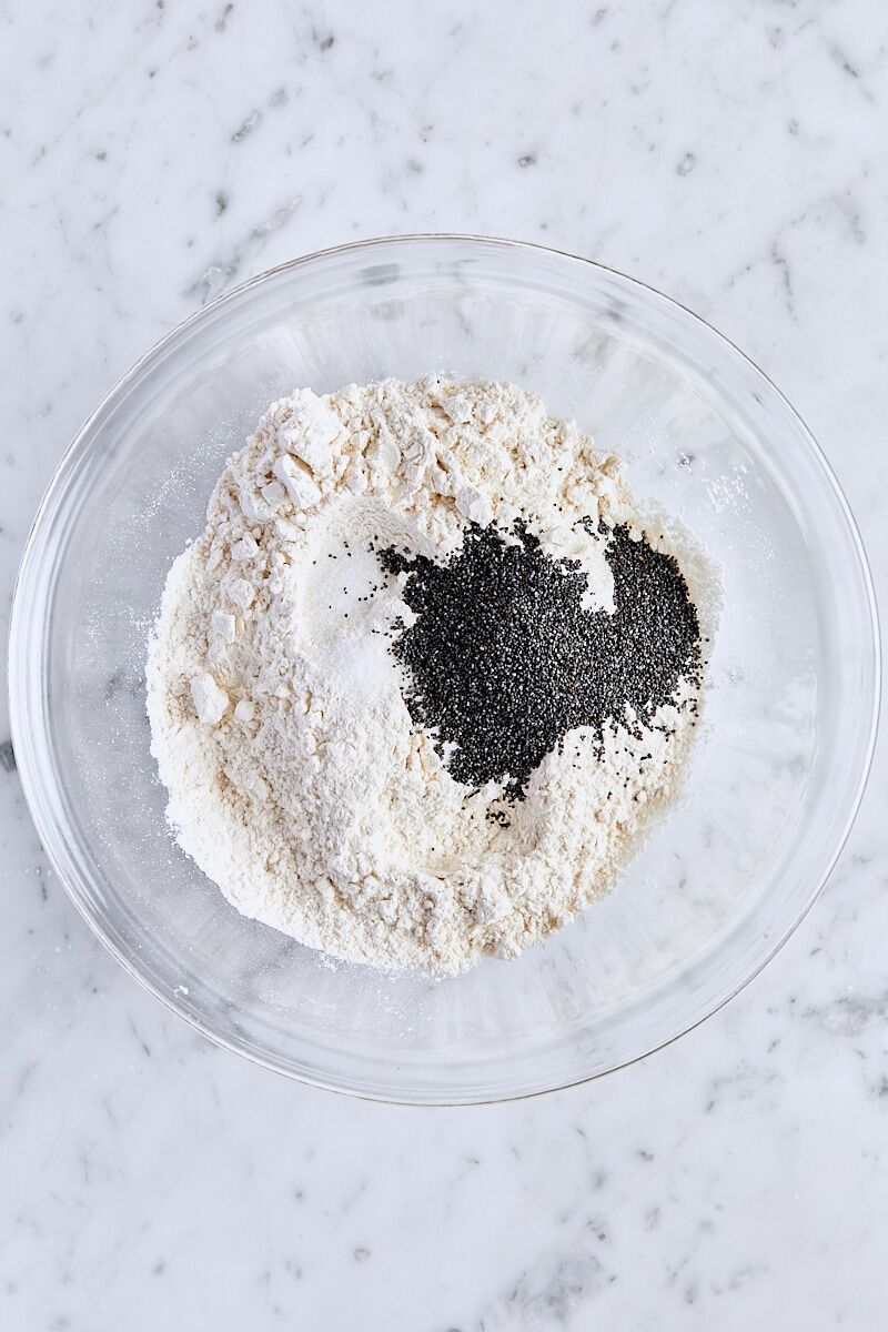 All-purpose flour, baking powder, baking soda, salt, and poppy seeds in glass bowl