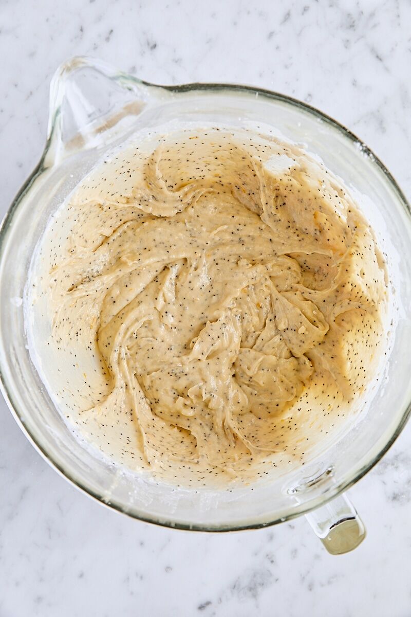 Mixed lemon poppy seed cake batter in glass mixer bowl