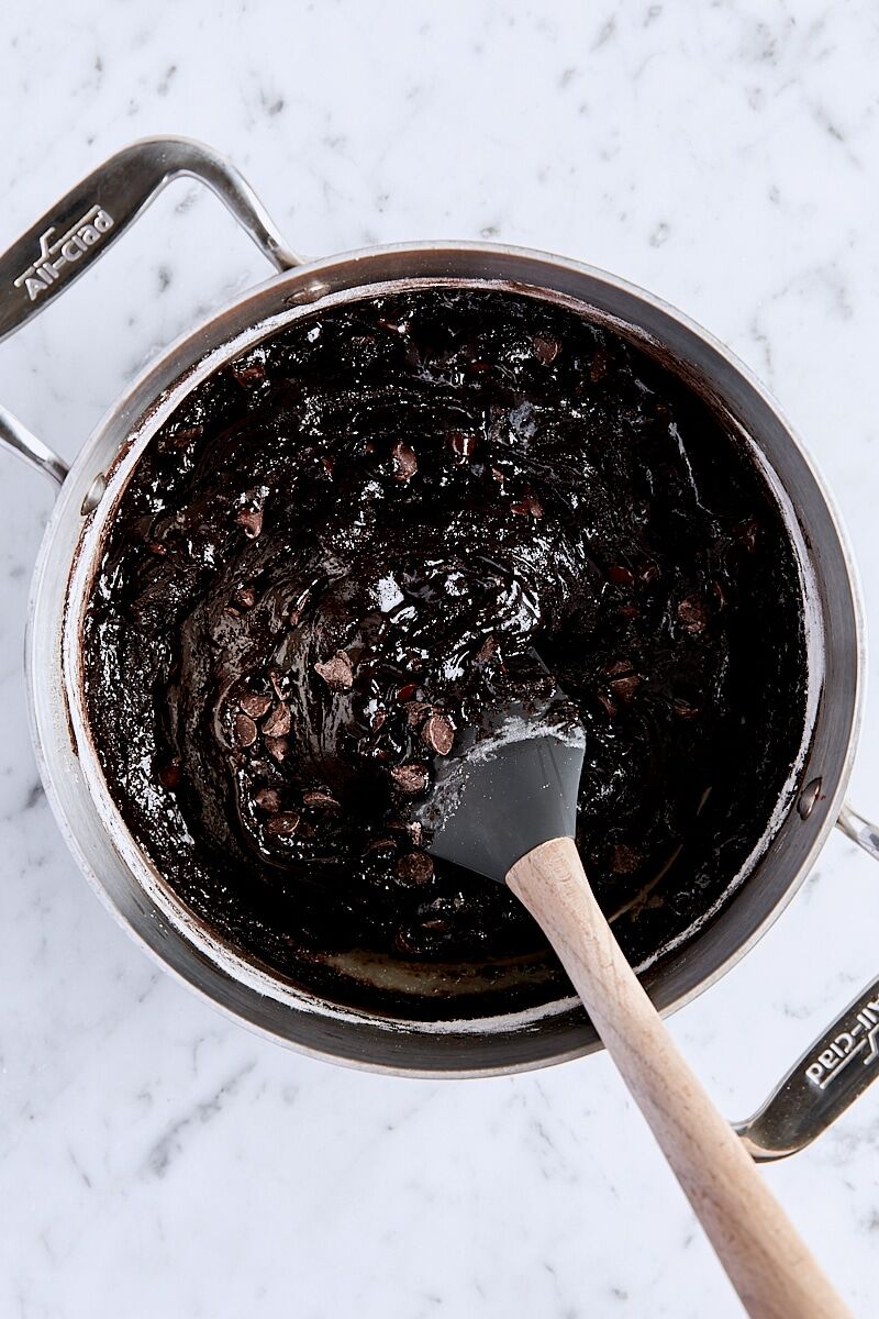 Mixed cocoa brownie batter in saucepan with spatula