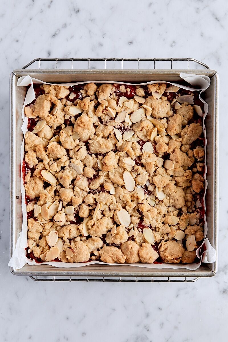Baked cherry pie bars in parchment-lined baking pan