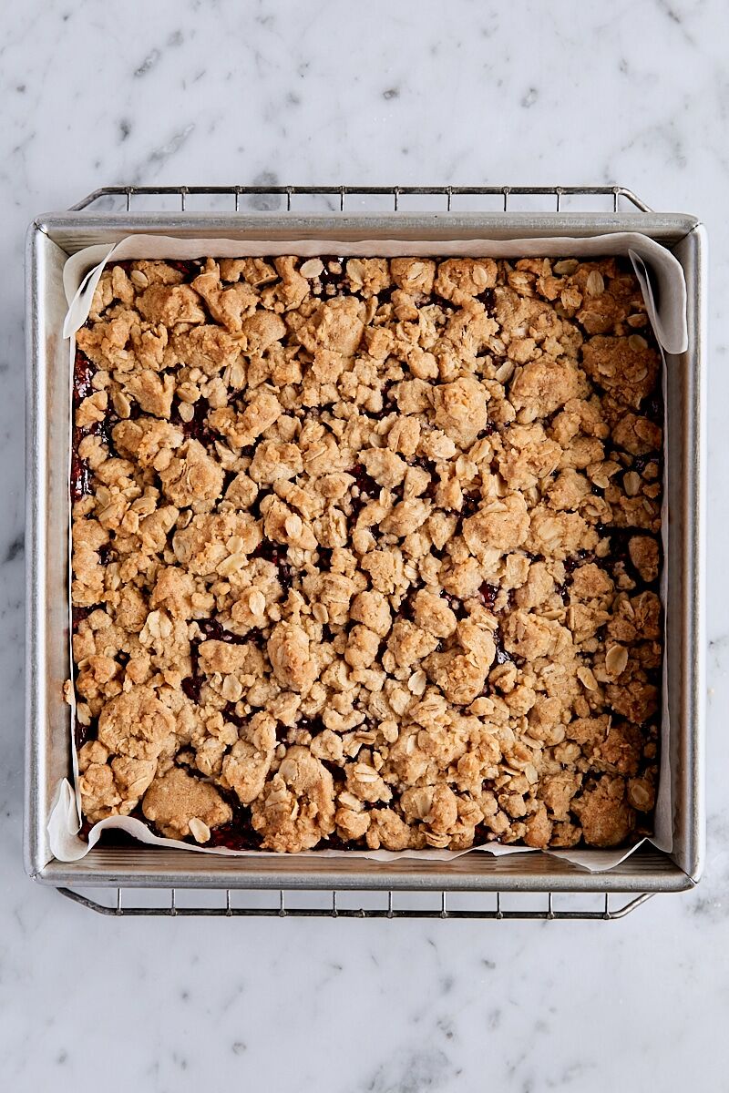 Baked raspberry crumble bars in parchment-lined baking pan