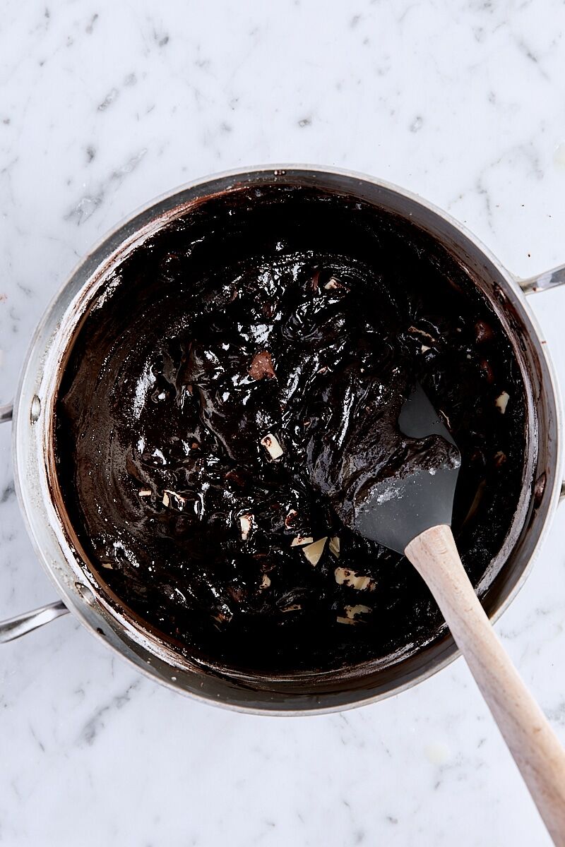 Mixed triple chocolate brownie batter in saucepan with spatula