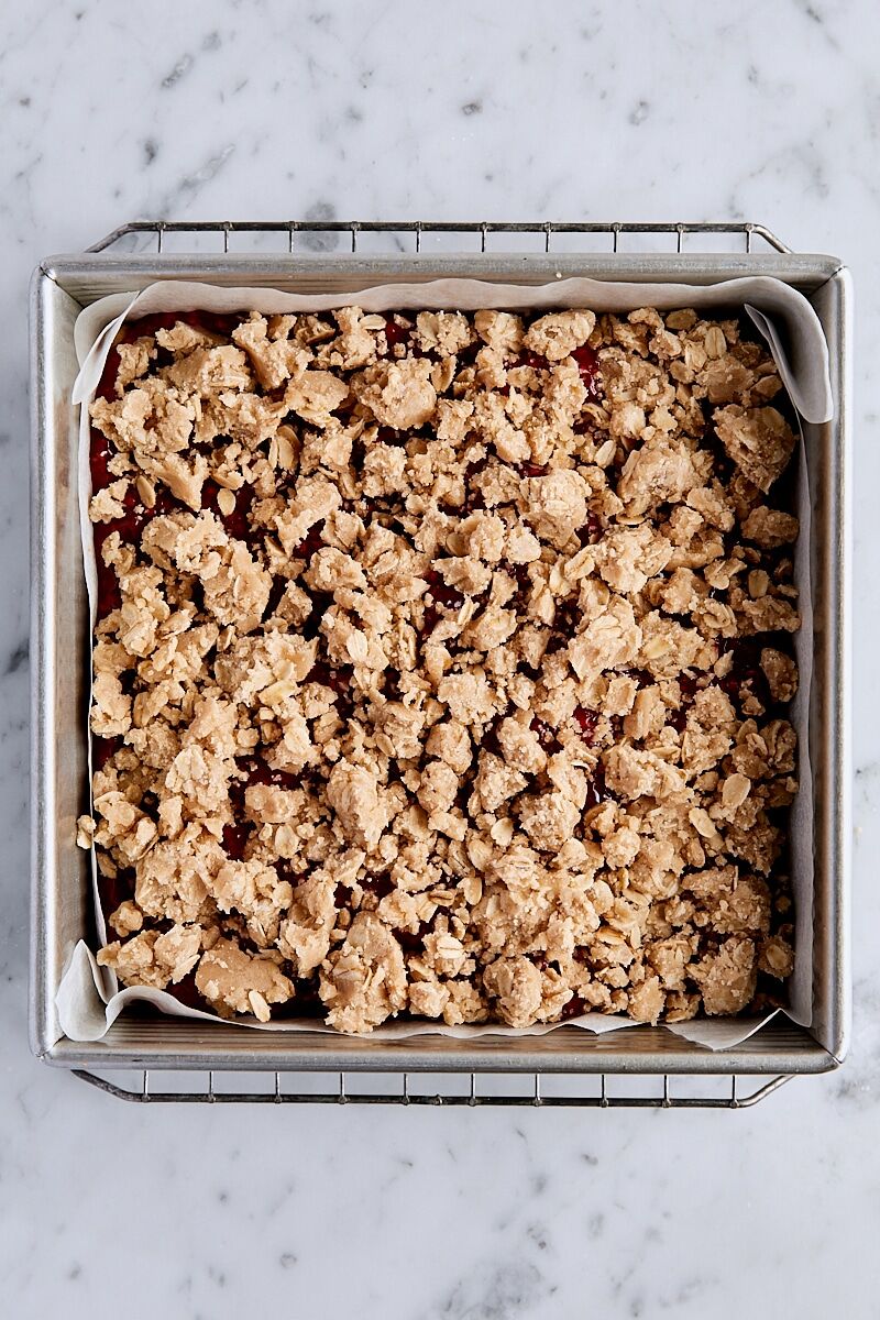 Crumble topping sprinkled over raspberry filling
