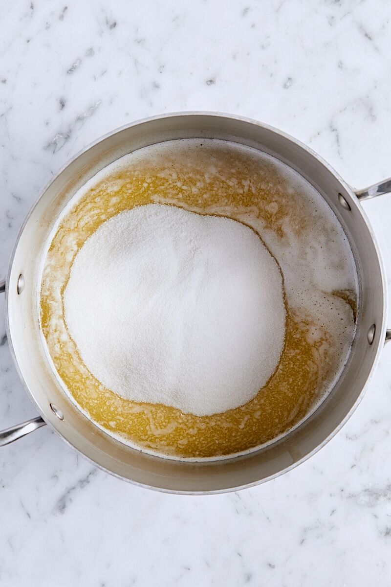 Granulated sugar added to saucepan with melted butter