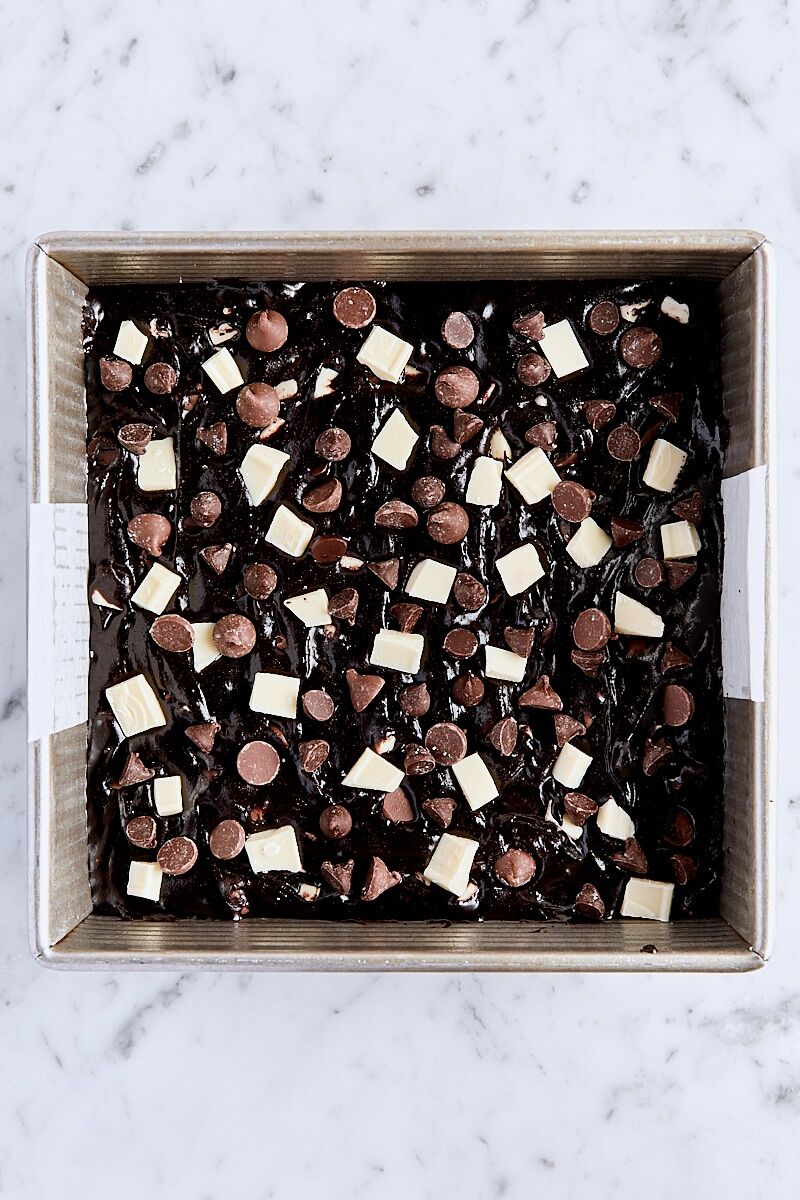 Triple chocolate brownie batter spread into parchment-lined square baking pan