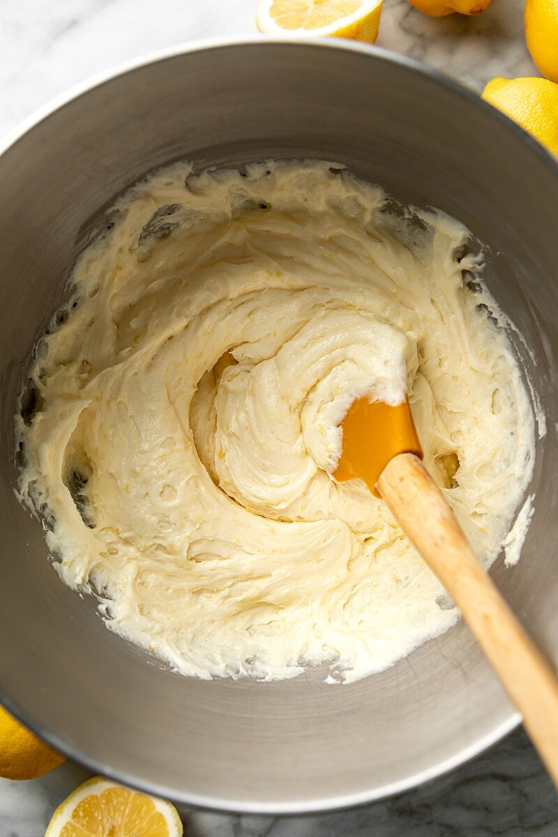 Lemon cream cheese frosting in mixer bowl with spatula