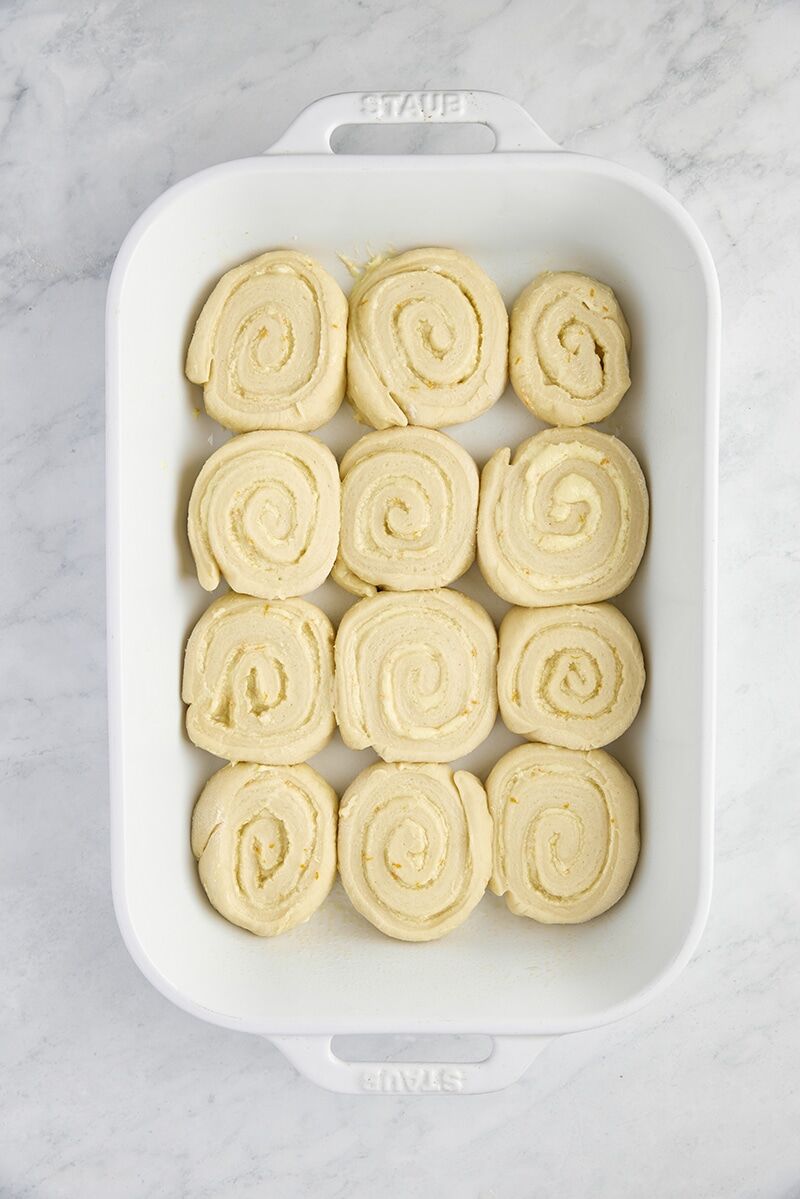 Unbaked orange rolls in ceramic baking dish