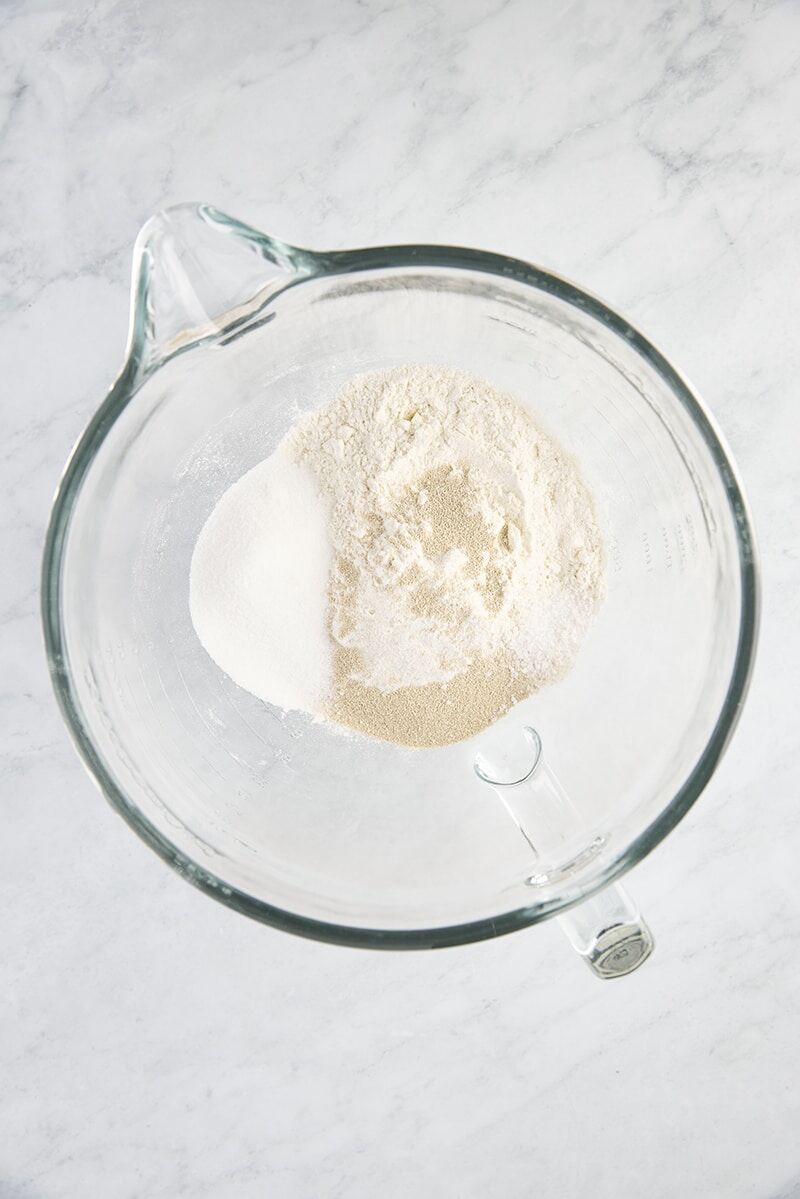 Flour, instant yeast, granulated sugar, and salt in glass mixer bowl