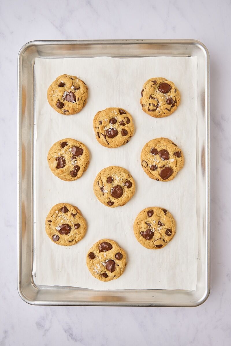 Baked cookies topped with flaky salt on parchment-lined baking sheet