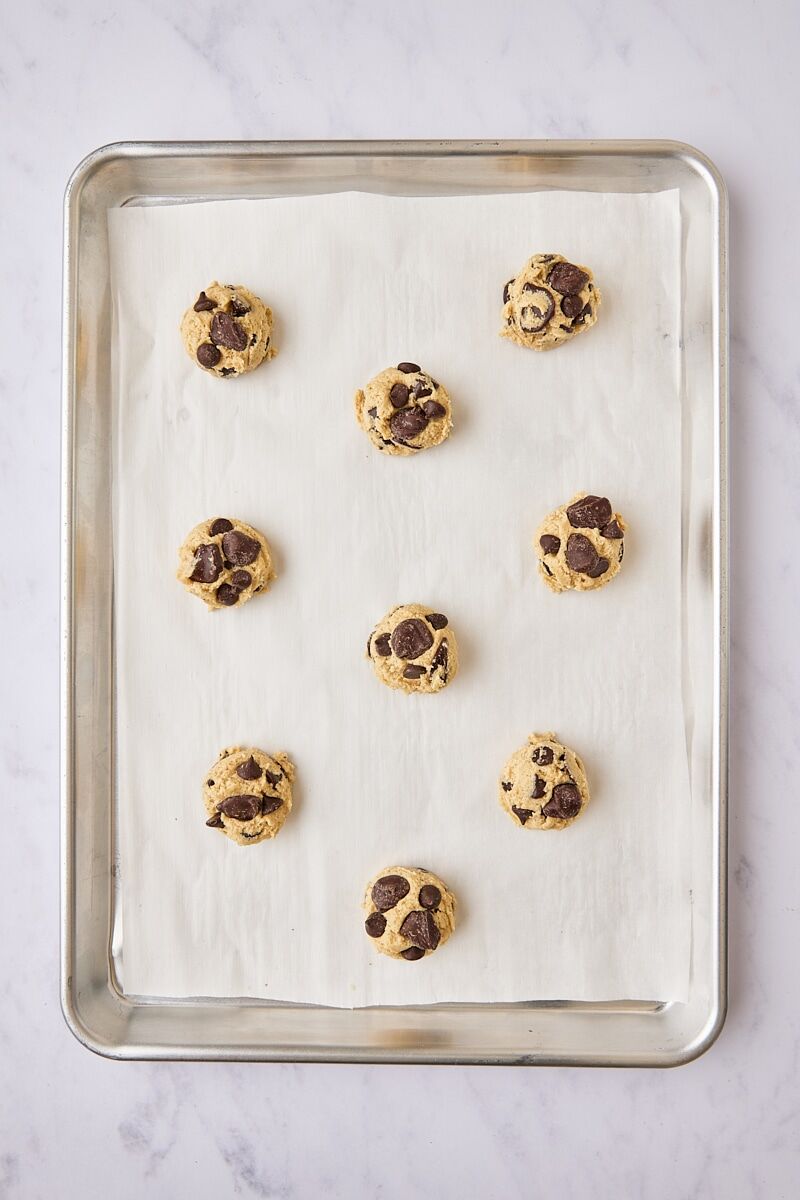 Chocolate chip cookie dough balls scooped onto parchment-lined baking sheet